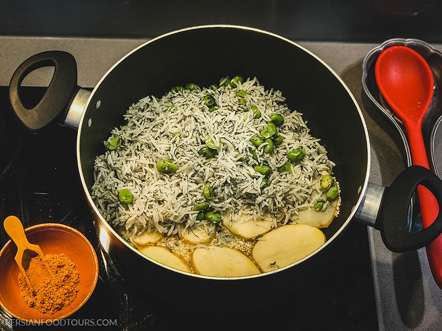 adding layers of rice and broad bean- baghali polo